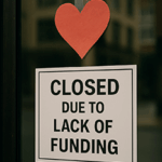 A paper heart is taped to a glass door above a sign that reads “Closed Due to Lack of Funding,” symbolizing the emotional impact of nonprofit closures and funding cuts.